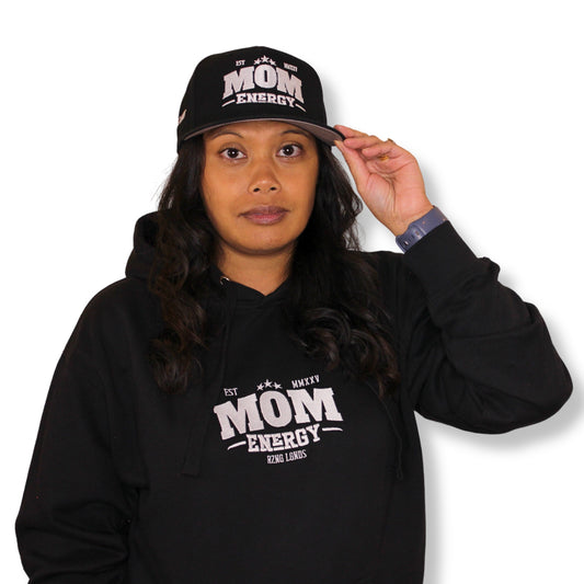 Person wearing a black hoodie and cap with 'Mom Energy' text on a white background